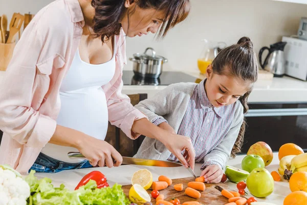 Mère avec sa fille tranchant des carottes — Photo de stock