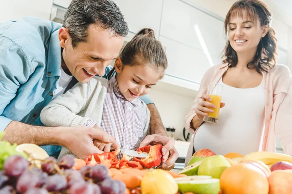 Cheerful family, pregnant mother with father helping daughter slicing pepper at kitchen — Stock Photo