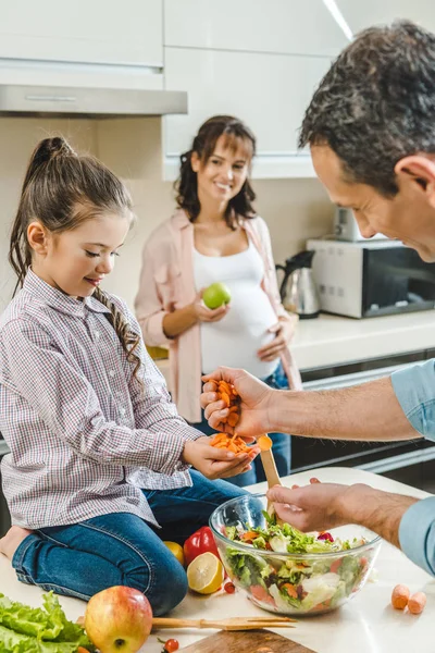 Feliz sorrindo família fazendo salada juntos na cozinha — Fotografia de Stock