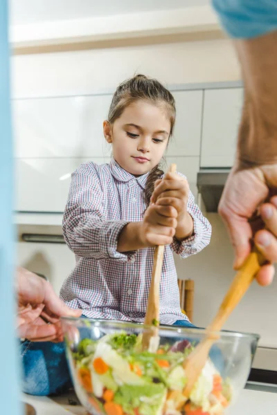 Kid mixed salad in bowl with dad — Stock Photo