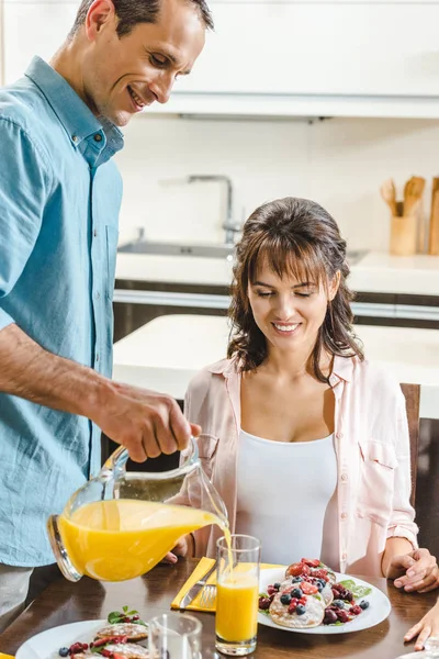 Man pouring juice in glass for woman — Stock Photo