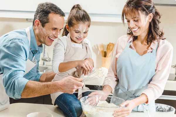 Счастливая кавказская семья в муке делает тесто на кухне — стоковое фото