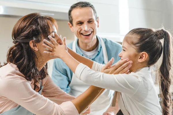 Allegra famiglia in cucina, madre e figlia si toccano delicatamente i volti e sorridono — Foto stock