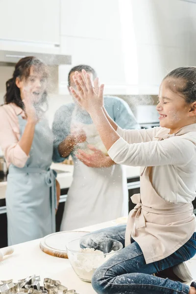 Família feliz, criança batendo palmas com farinha na cozinha — Fotografia de Stock