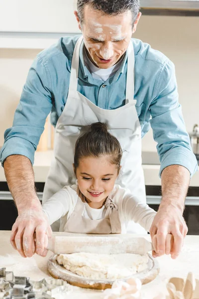 Отец с дочерью раскатывают тесто — стоковое фото