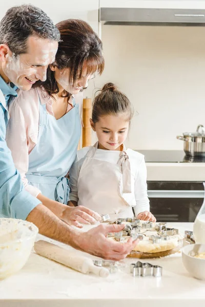 Happy caucasian family in flour making forms of dough at kitchen — Stock Photo