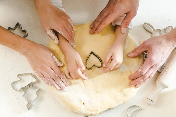 Vue de dessus des mains de la famille sur la pâte avec des formes — Photo de stock