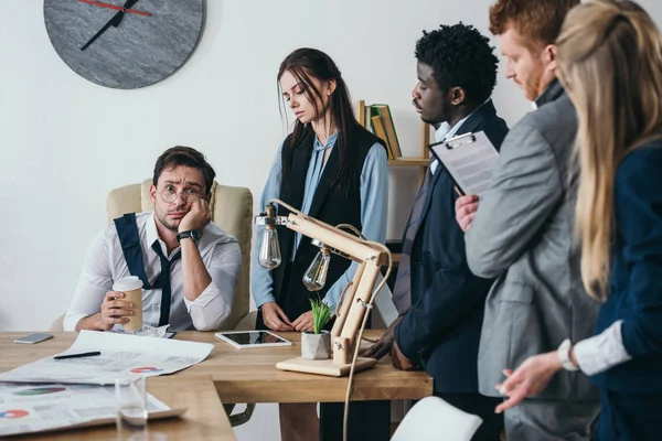 Grupo de jóvenes gerentes hablando con el jefe con exceso de trabajo - foto de stock