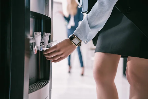 Plan recadré de femme d'affaires versant de l'eau du distributeur — Photo de stock