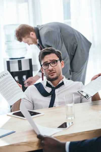 Exhausted businessman with paperwork sitting at office — Stock Photo