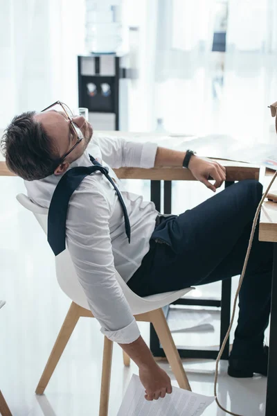 Müder junger Geschäftsmann schläft auf Stuhl am Büroarbeitsplatz — Stockfoto