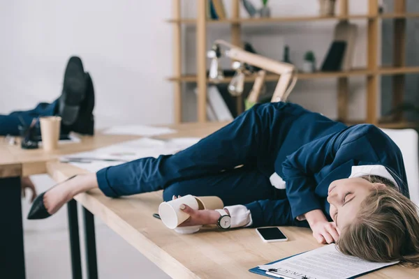 Überarbeitete Geschäftsfrau schläft auf Tisch im chaotischen Büro — Stock Photo