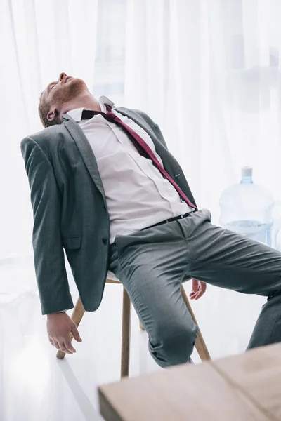 Hombre de negocios agotado durmiendo en la silla en la oficina - foto de stock