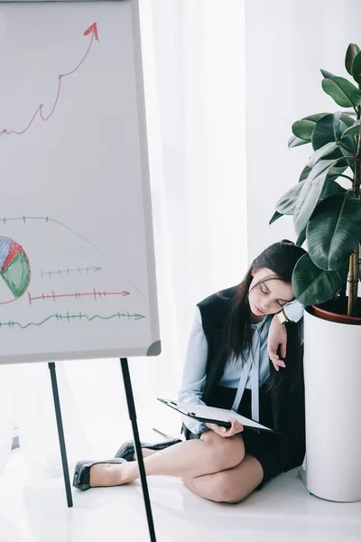 Businesswoman sleeping at office while leaning on flower pot — Stock Photo