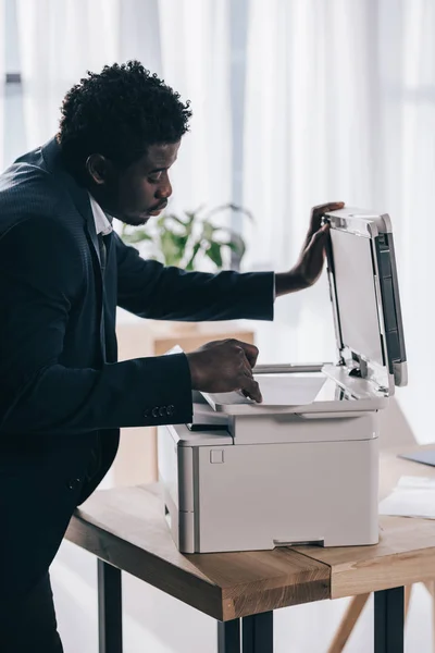 Gerente afroamericano usando fotocopiadora en la oficina - foto de stock