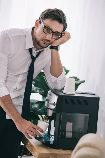 Übermüdeter Geschäftsmann schüttet gelangweilten Kaffee aus Büromaschine — Stockfoto