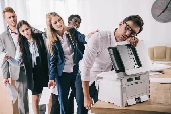 Exhausted businessman sleeping on copier while his colleagues standing in queue behind him — Stock Photo