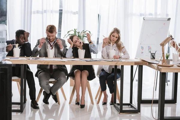 Группа уставших менеджеров, которые вместе едят лапшу в офисе — стоковое фото