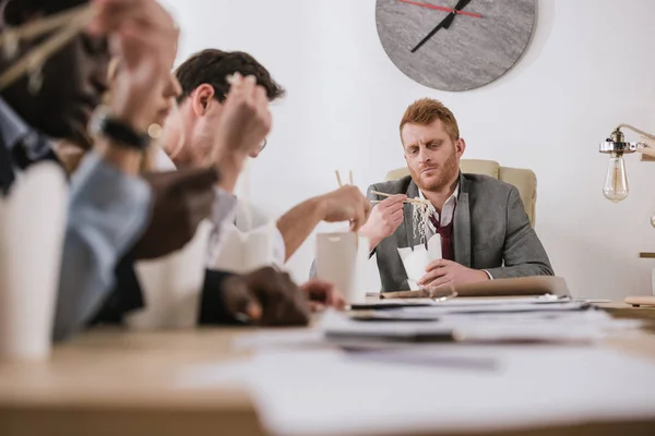 Група бізнесменів, які їдять локшину разом в офісі з босом — стокове фото