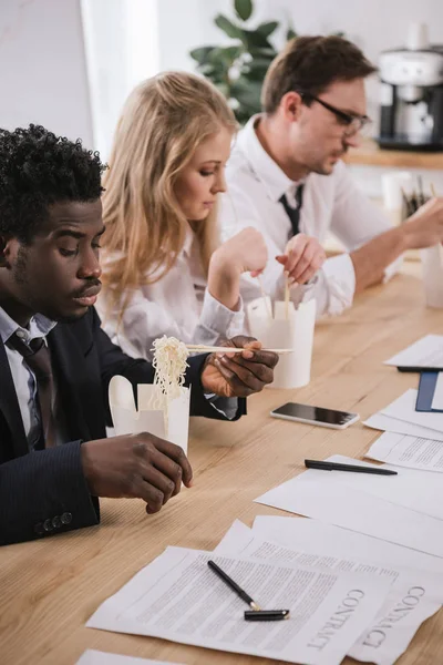 Tired businesspeople eating noodles in conference hall at office — Stock Photo