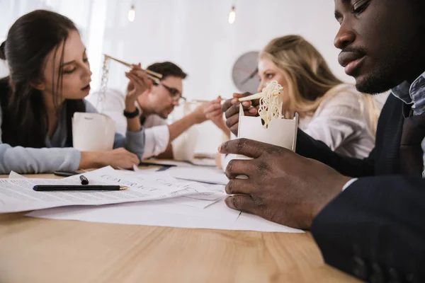 Gros plan de gens d'affaires mangeant des nouilles ensemble au bureau — Photo de stock