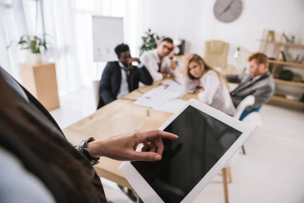 Close-up shot of businesswoman using tablet with blurred colleagues sitting on background — Stock Photo