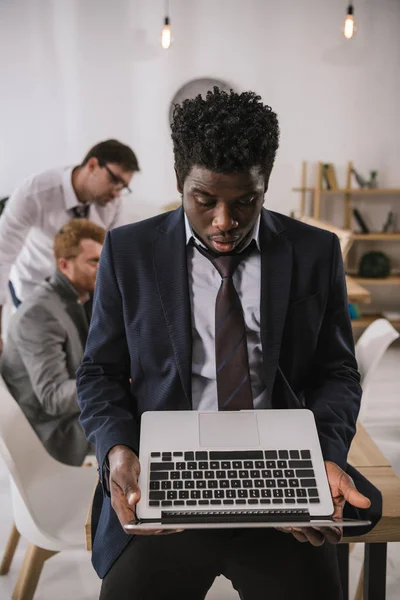 Chocado jovem empresária olhando para laptop enquanto se inclina de volta na mesa na sala de conferências — Fotografia de Stock