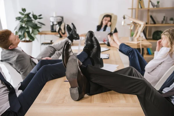 Бизнесмены сидят в конференц-зале с ногами на столе — стоковое фото
