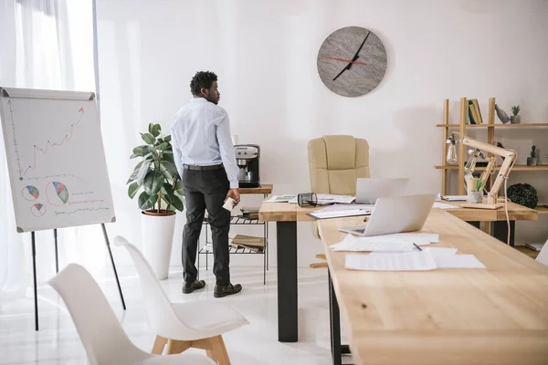 Empresário exausto solitário em pé na sala de conferências com papelada na mesa — Fotografia de Stock