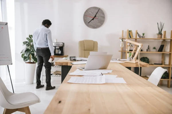 Самотній втомлений бізнесмен стоїть в конференц-залі з паперовими роботами на столі — стокове фото