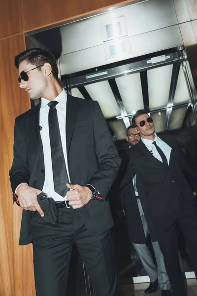 Bodyguard putting hand on gun when going out from elevator with politician — Stock Photo