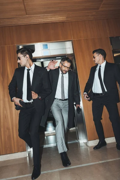 Celebridade saindo do elevador e cobrindo cara a mão — Fotografia de Stock