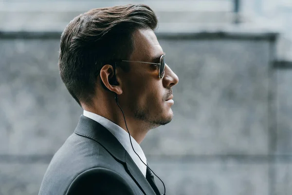 Profile of handsome bodyguard with sunglasses and security earpiece — Stock Photo