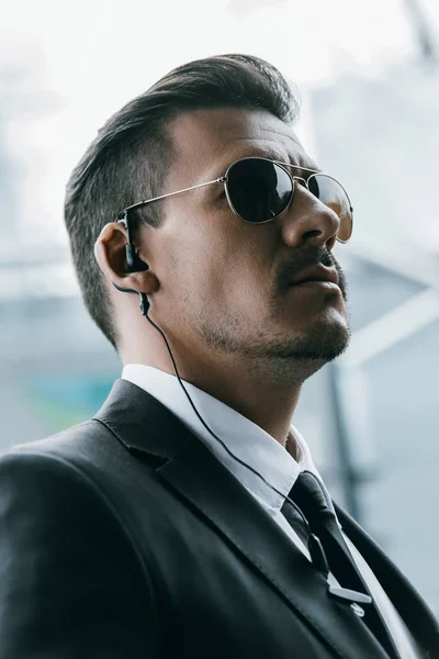 Portrait of handsome security guard in sunglasses and security earpiece — Stock Photo