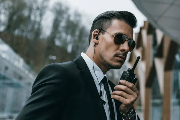 Serious handsome security guard talking by portable radio — Stock Photo