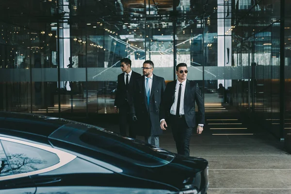 Geschäftsmann und zwei Leibwächter zu Fuß zum Auto — Stockfoto