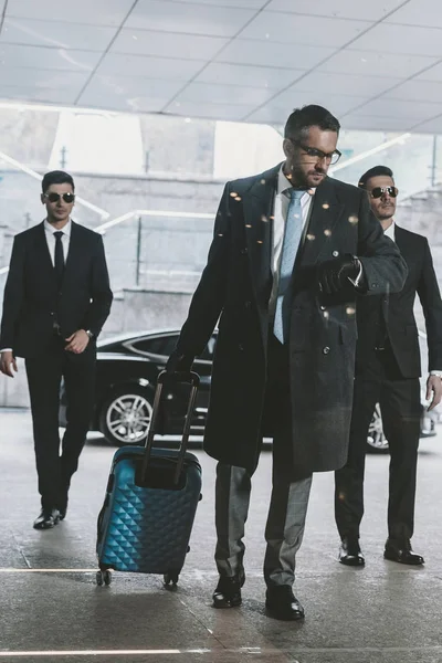 Geschäftsmann läuft mit Reisetasche aus Auto und schaut auf Uhr — Stockfoto
