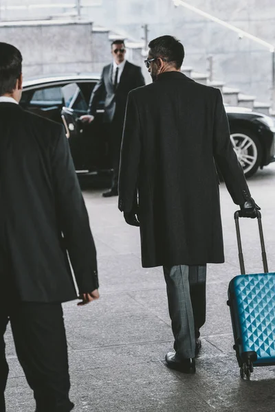 Hombre de negocios va con azul bolsa de viaje a coche - foto de stock