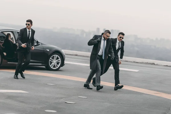 Bodyguards protecting businessman on his way from car — Stock Photo