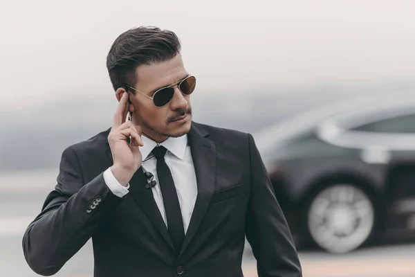 Handsome bodyguard listening message with security earpiece — Stock Photo