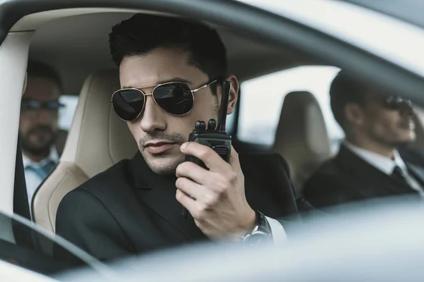 Bodyguard in sunglasses talking by portable radio — Stock Photo