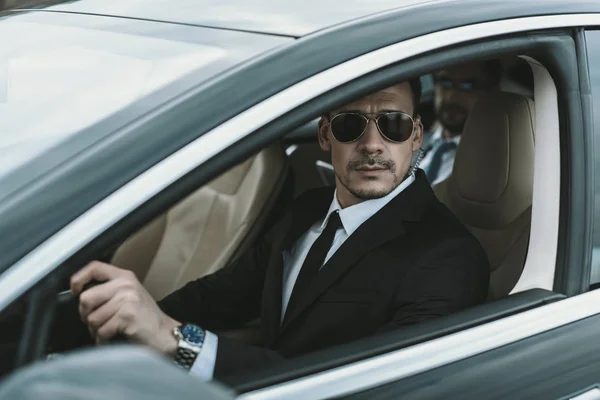 Guardaespaldas sentado en el coche con el hombre de negocios y mirando hacia otro lado — Stock Photo