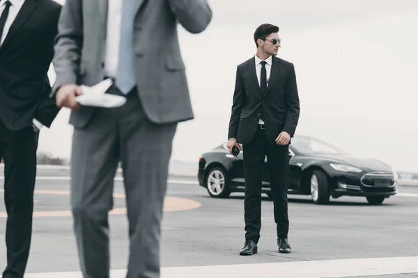 Immagine ritagliata di guardie del corpo e uomo d'affari che cammina su eliporto da auto — Foto stock