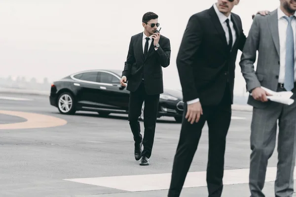 Cropped image of bodyguard talking by portable radio — Stock Photo