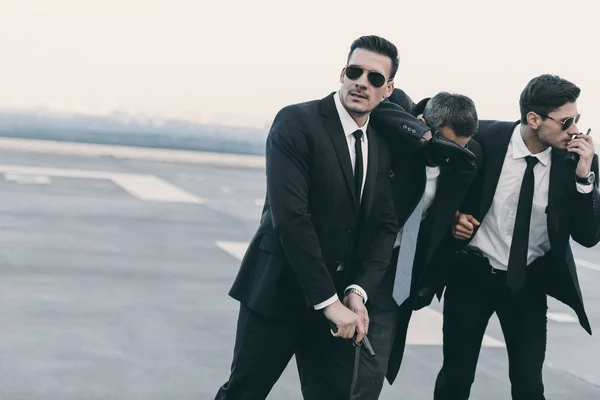 Two bodyguards protecting businessman with gun — Stock Photo