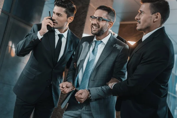 Security guards standing with laughing male suspect — Stock Photo