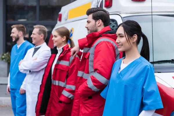 Лікарі швидкої допомоги робоча команда стоїть і позує перед автомобілем — стокове фото