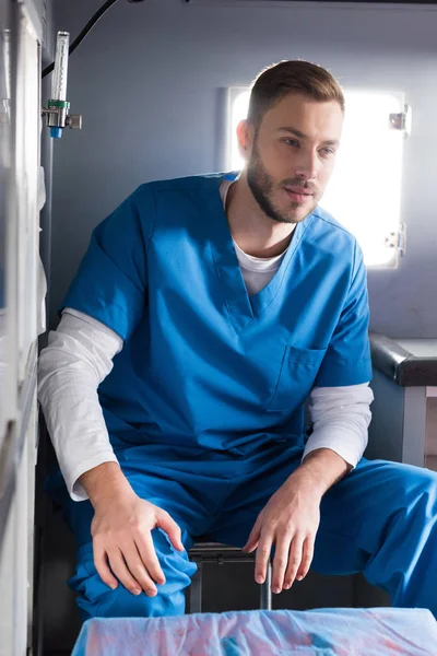 Cheerful handsome male doctor sitting in ambulance — Stock Photo