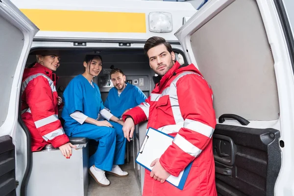 Equipo de trabajo de paramédicos sonriendo y mirando hacia otro lado - foto de stock