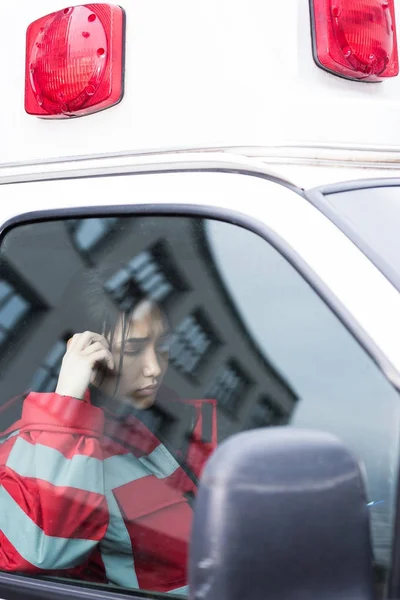 Joven hembra asiático paramédico leyendo algo en ambulancia - foto de stock